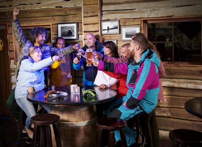Groep mensen die er blij uitzien met winterkleding en drankjes aan een bar