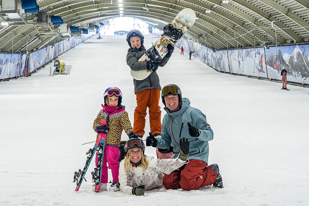 Kinderen en ouder poseren voor een foto op de piste