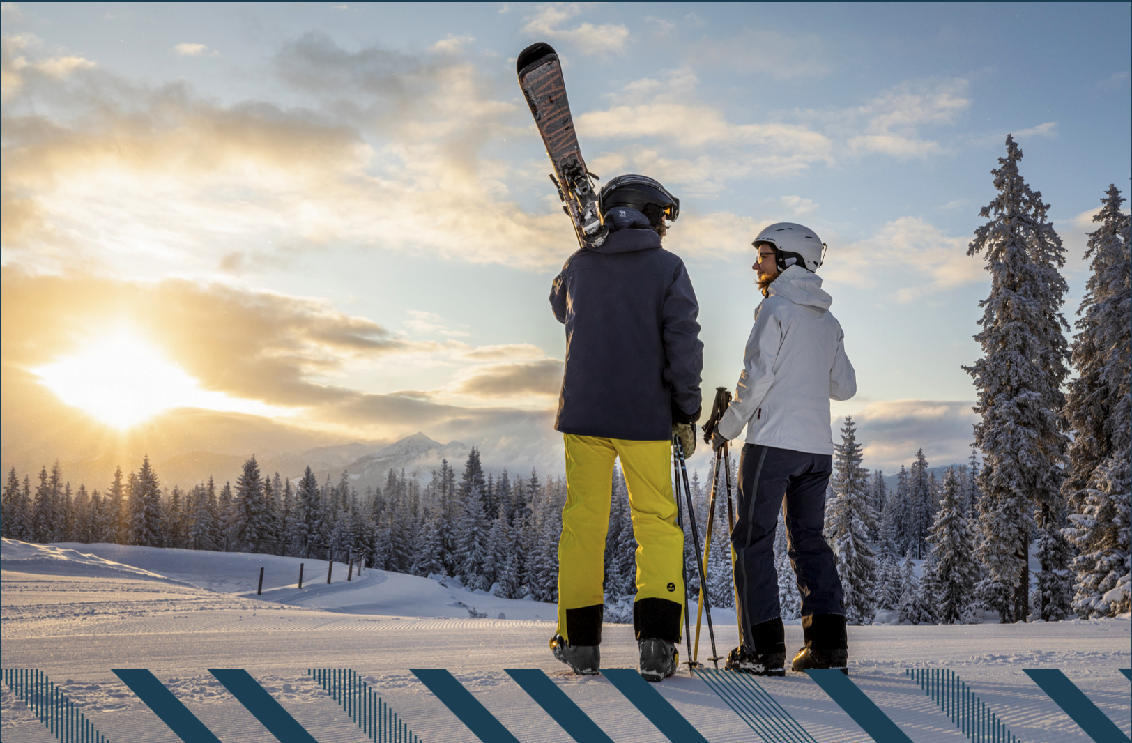 Twee personen staan op sneeuw met skis en kijken naar een zonsopgang