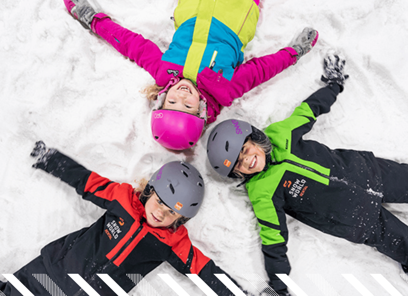 Drie kinderen die op sneeuw liggen met hun armen gespreid