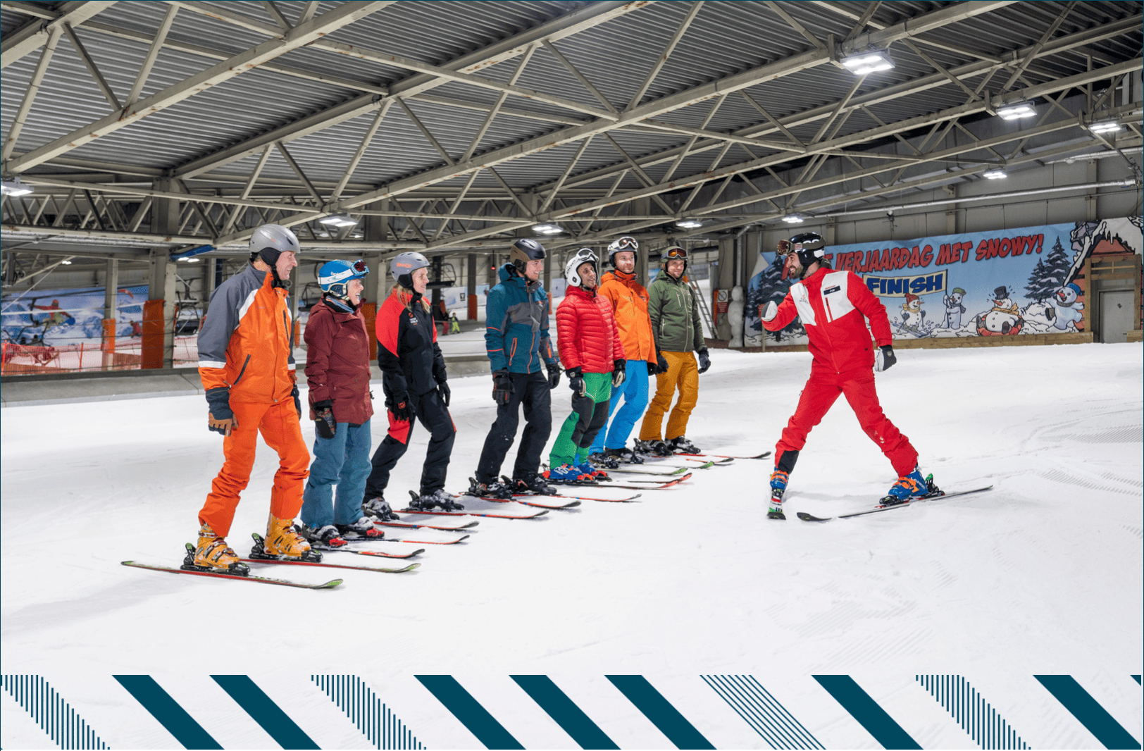 Een leraar met een klas leerlingen allemaal op skis op een piste